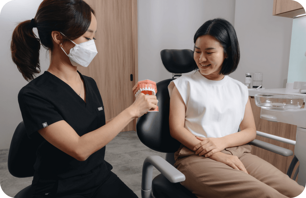 Photo of a dentist showing a patient how to brush on a model teeth