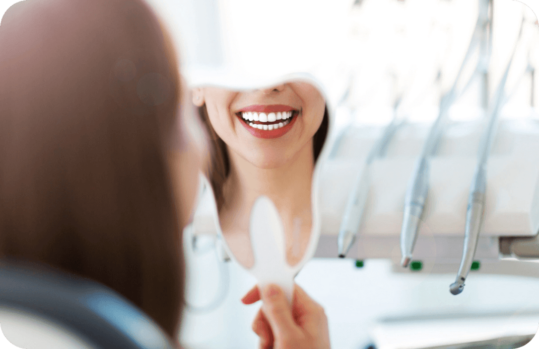 Photo of a woman looking at a mirror, showing her white teeth